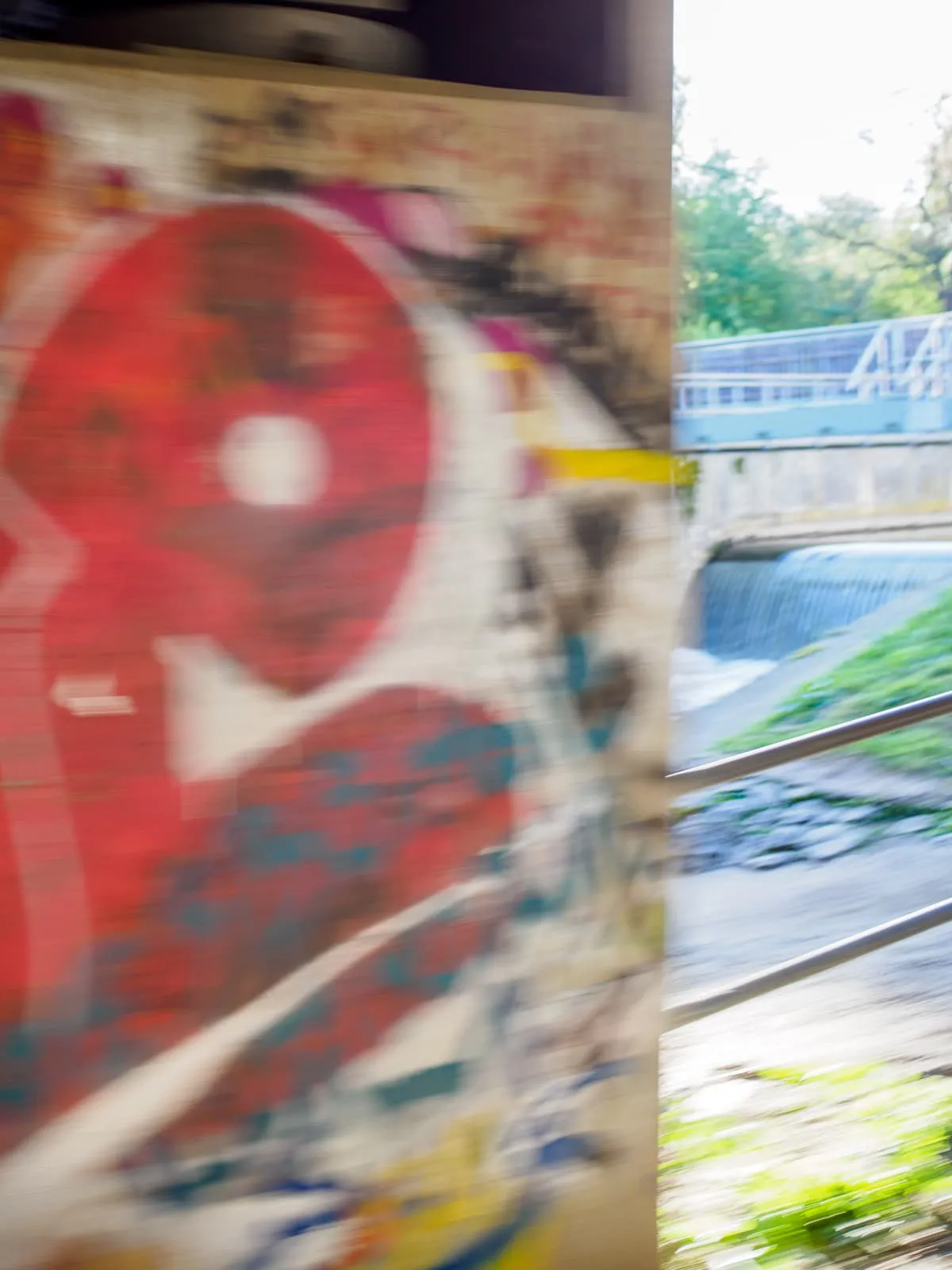 Blurred red graffiti on a wall beside a river, 2026