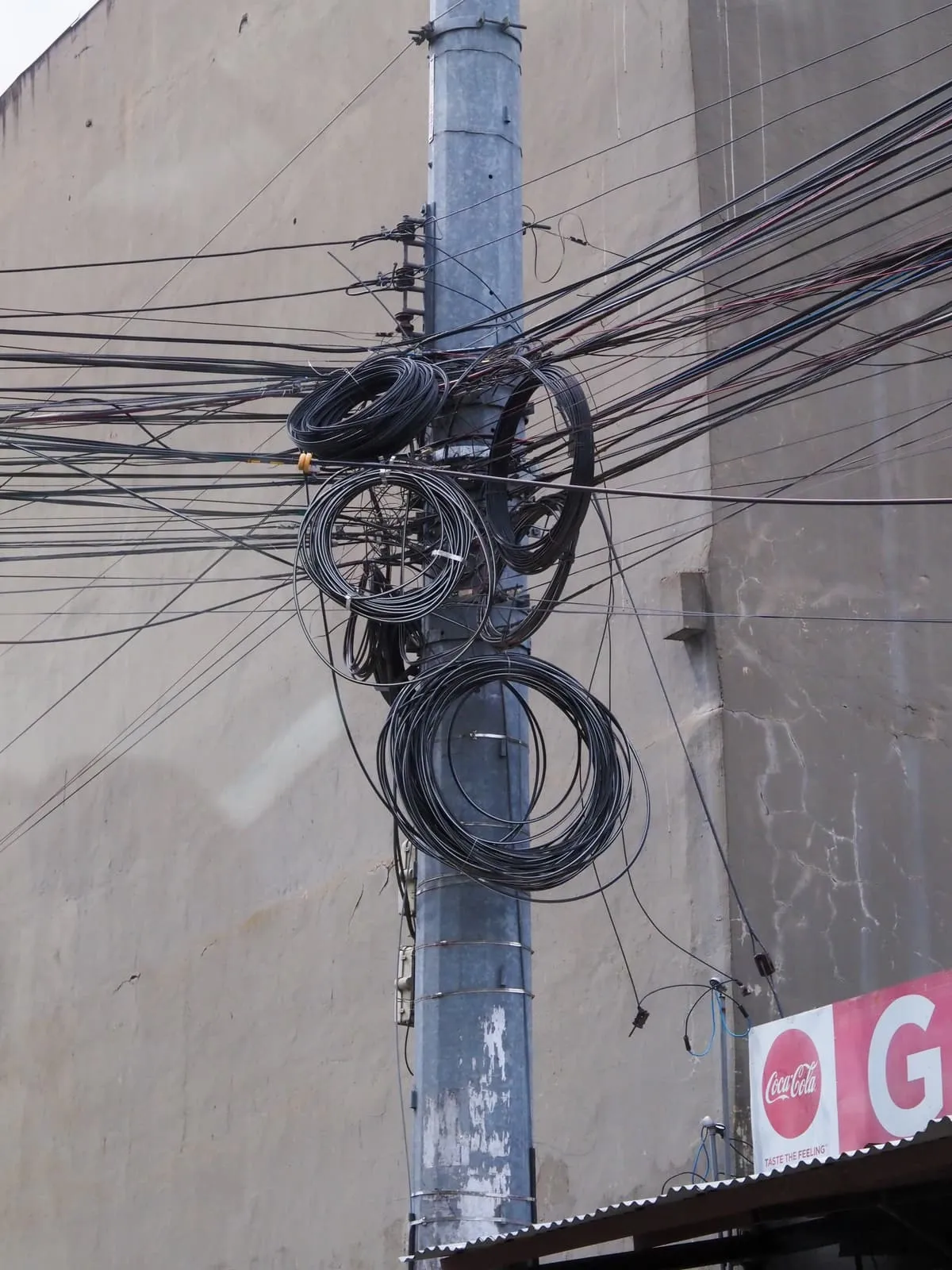 Utility pole with coils of black cable and many wires, 2024
