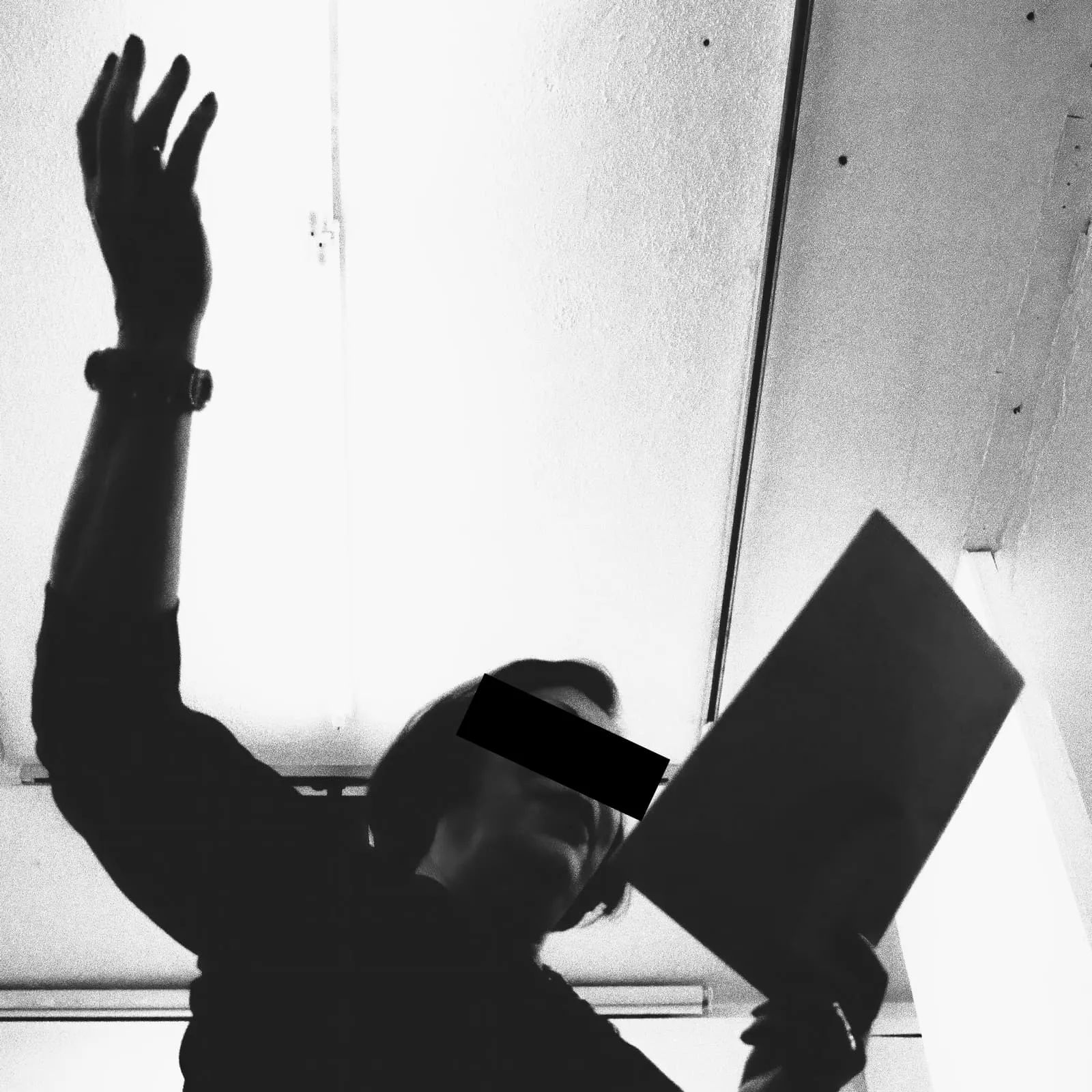 Black and white, a woman with raised arm holding a folder, eyes barred
