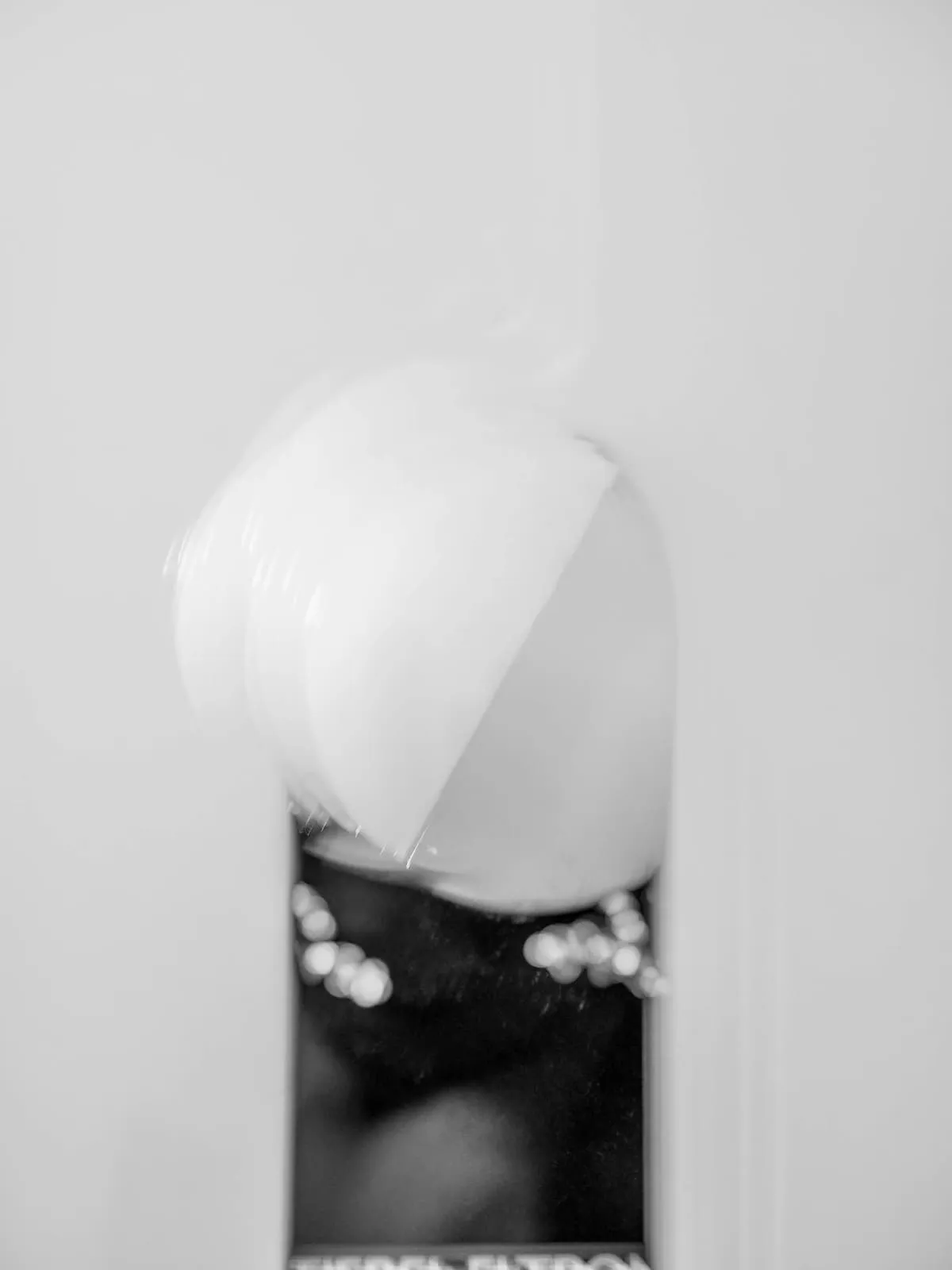 Black and white bare bulb against a white wall, 2020