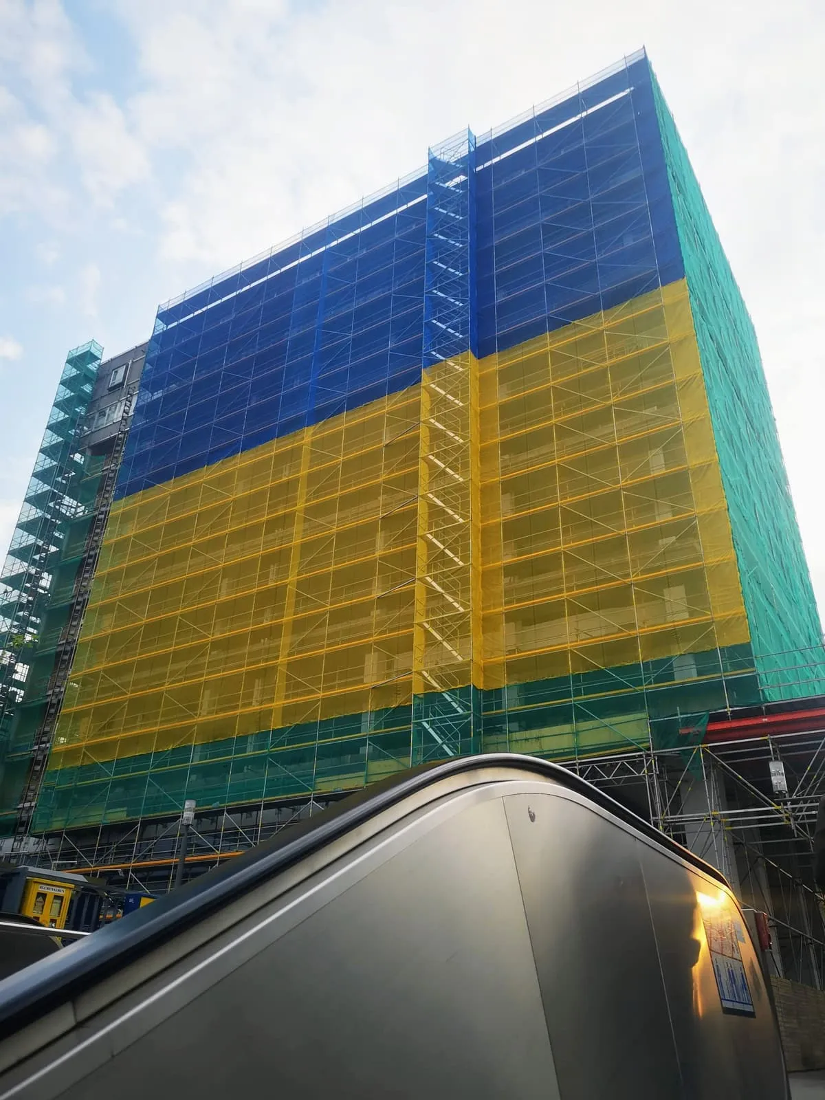 Scaffolded block wrapped in blue and yellow netting, 2022