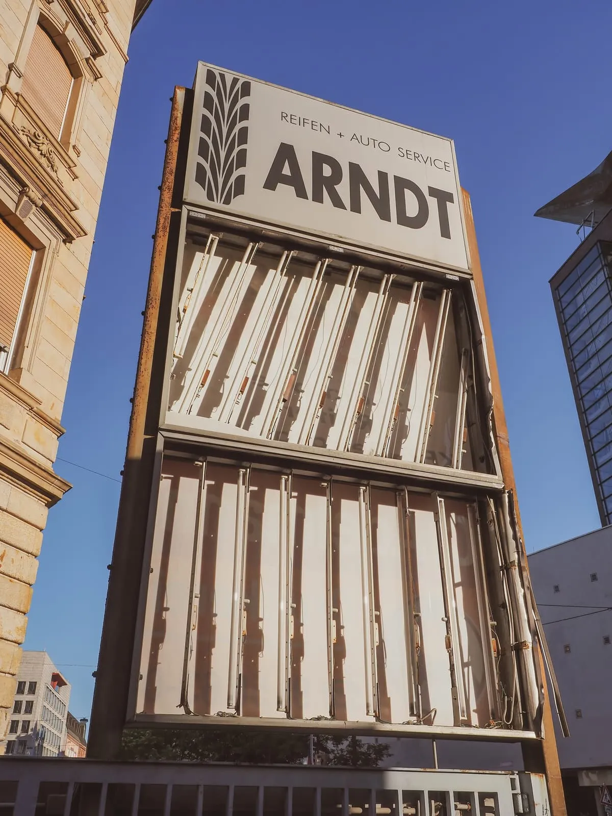 Tall slatted sign reading Arndt against a blue sky, 2020