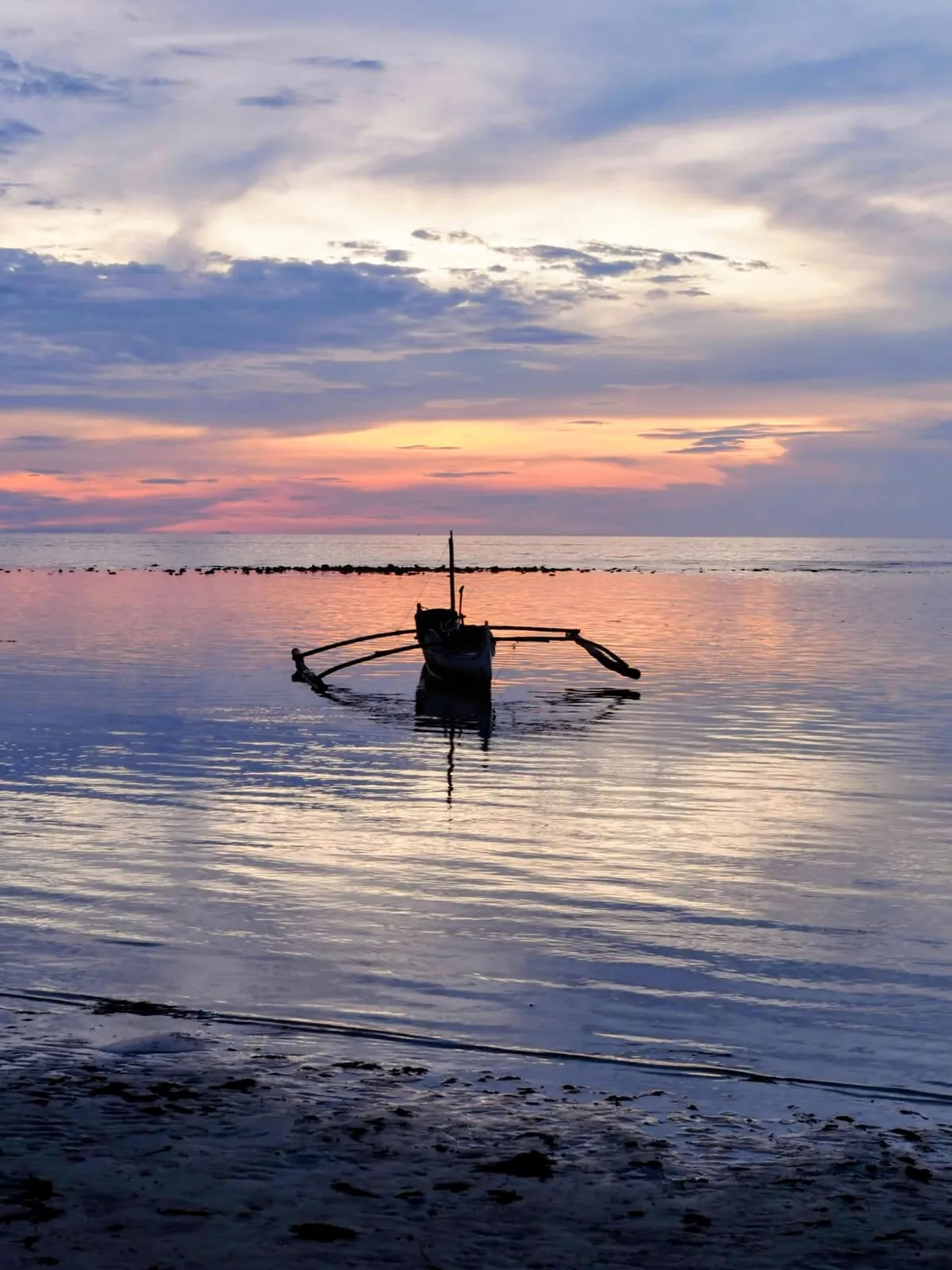 Outrigger boat on flat water at sunset, 2024