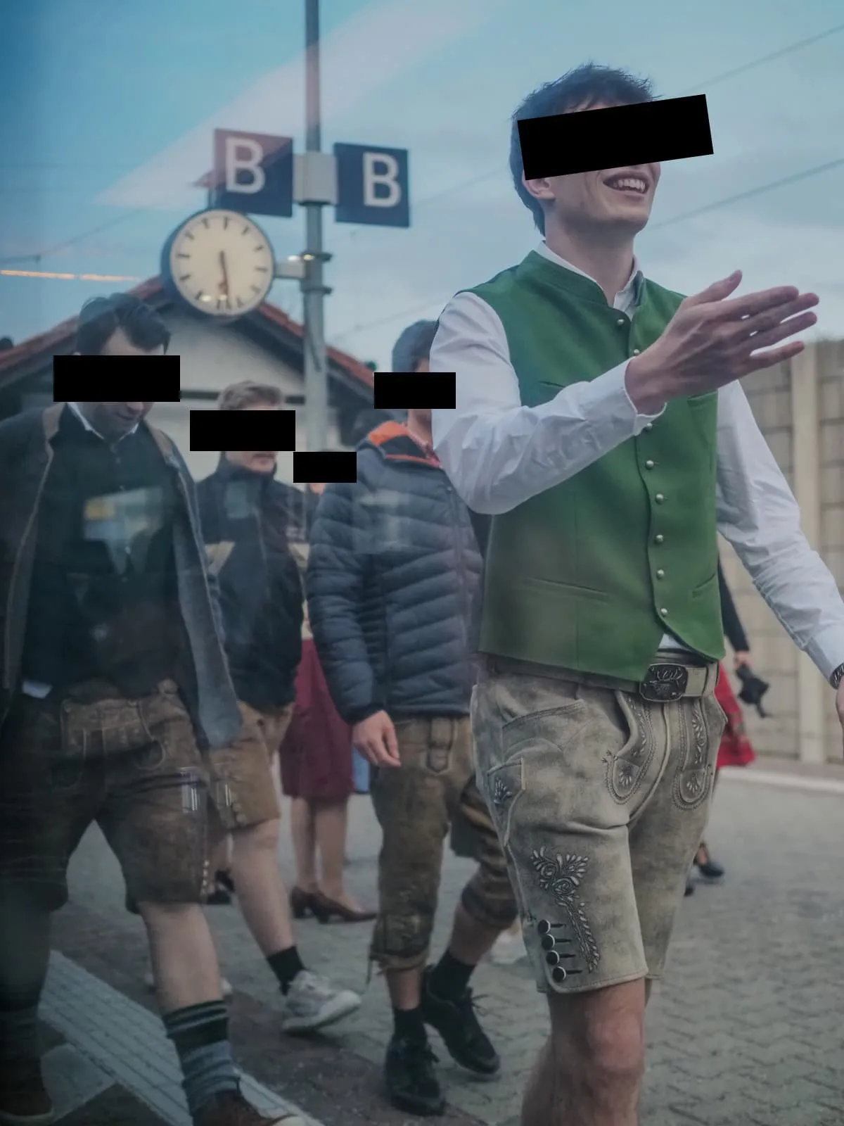 Men in lederhosen walking along a platform, eyes barred, 2026
