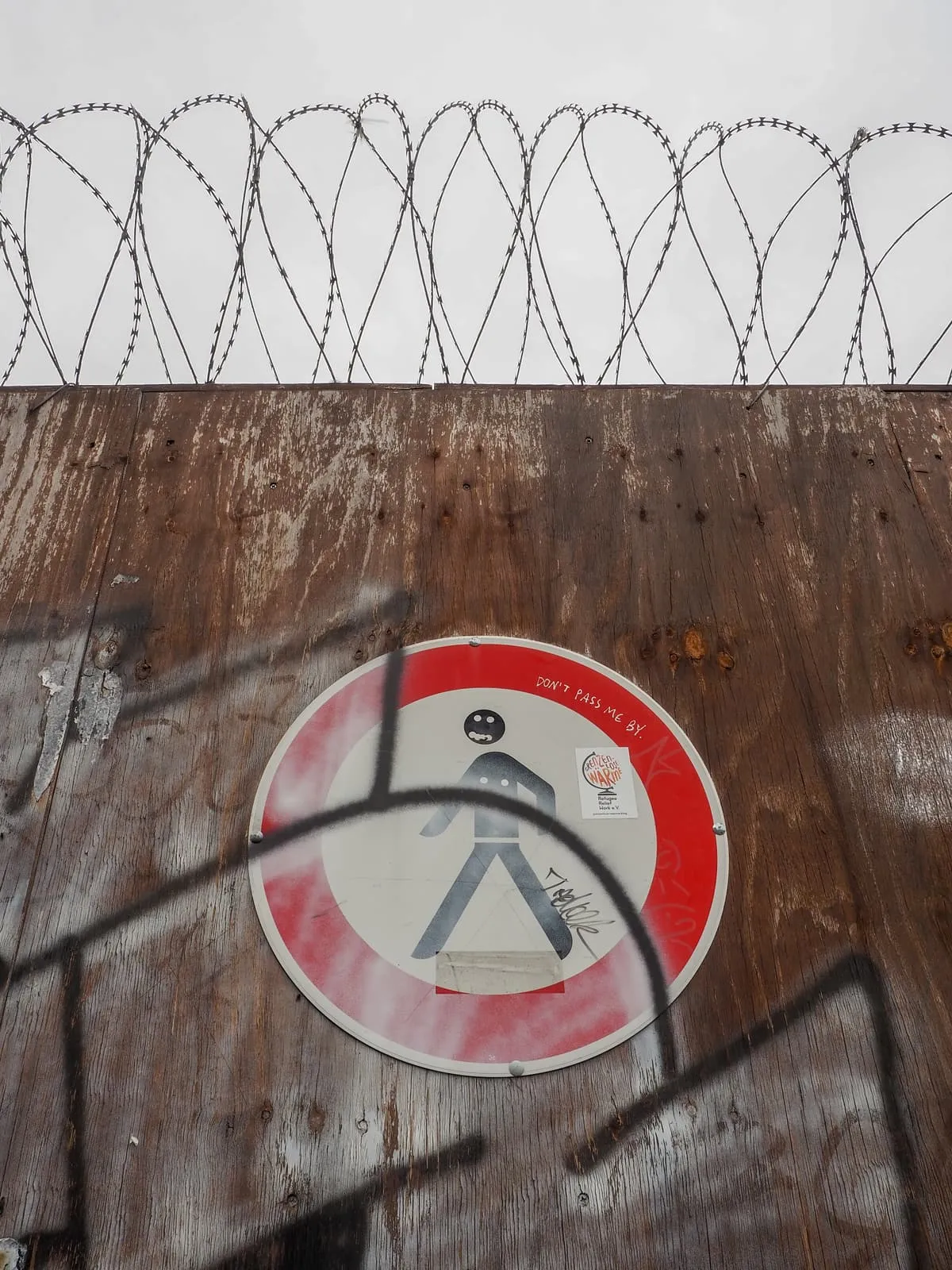No pedestrians sign on a rusty wall under razor wire, 2020