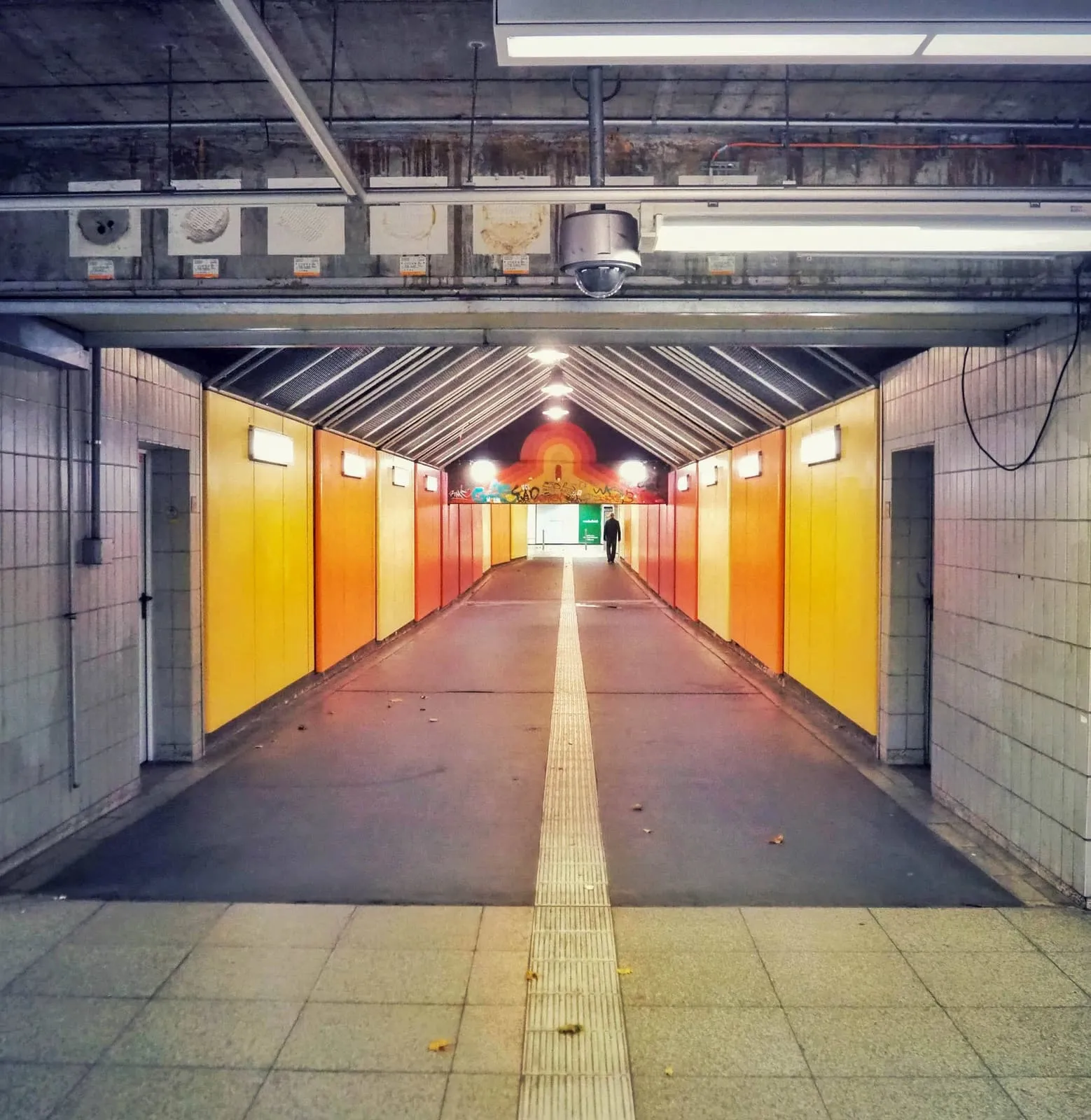 Orange and yellow underpass leading to a lit exit