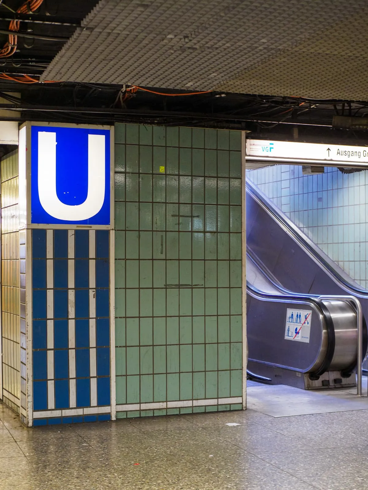 Underground station pillar with a blue U sign and an escalator, 2026