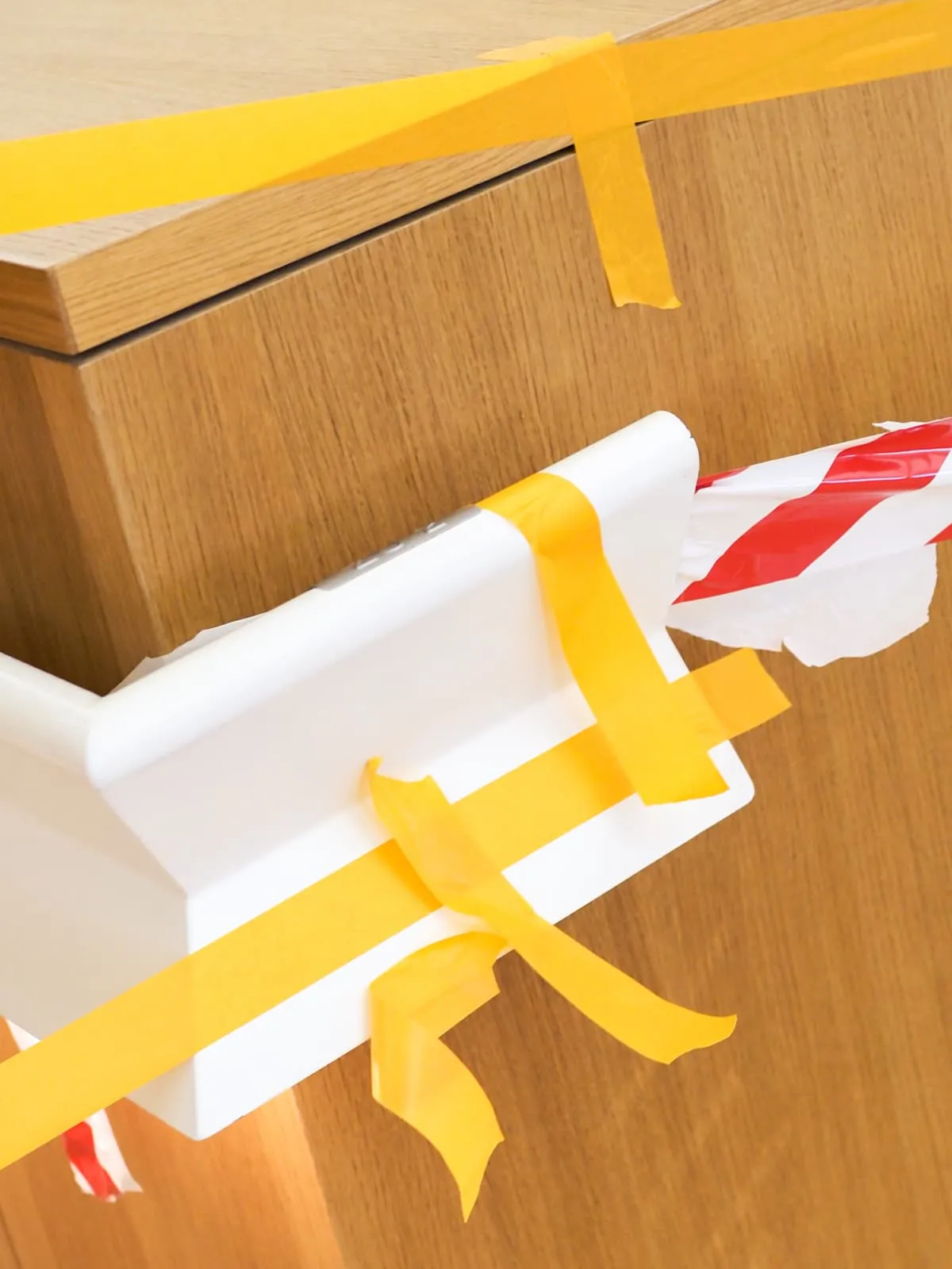 White box bound with yellow tape on a wooden floor, 2026