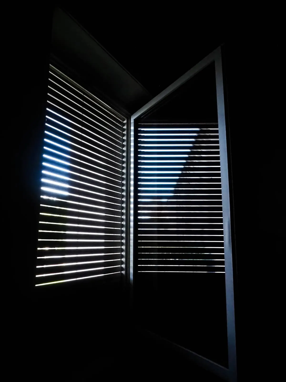 Dark room, light coming through two slatted shutters, 2020