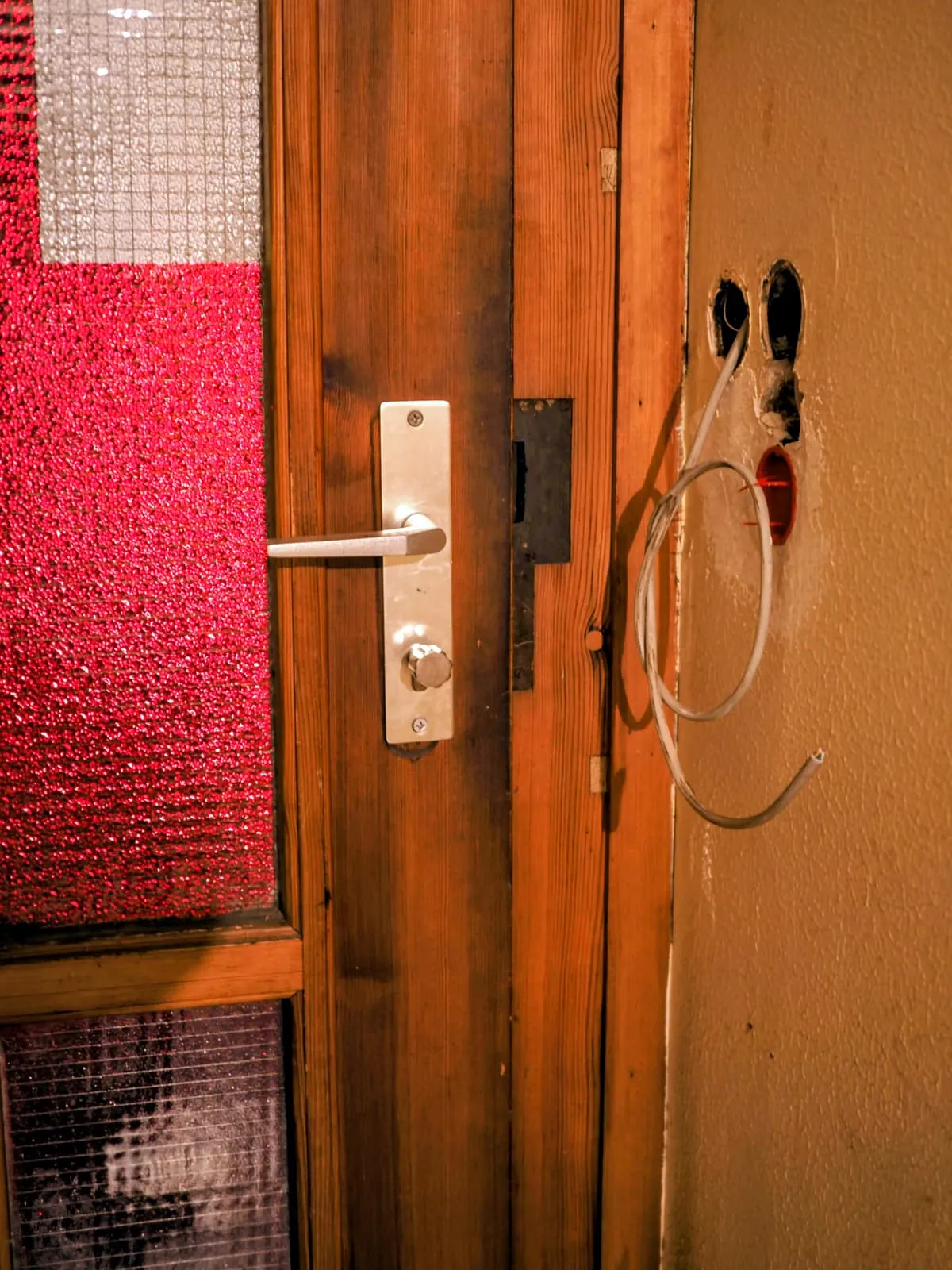 Wooden door with a handle and two holes where locks were, 2025