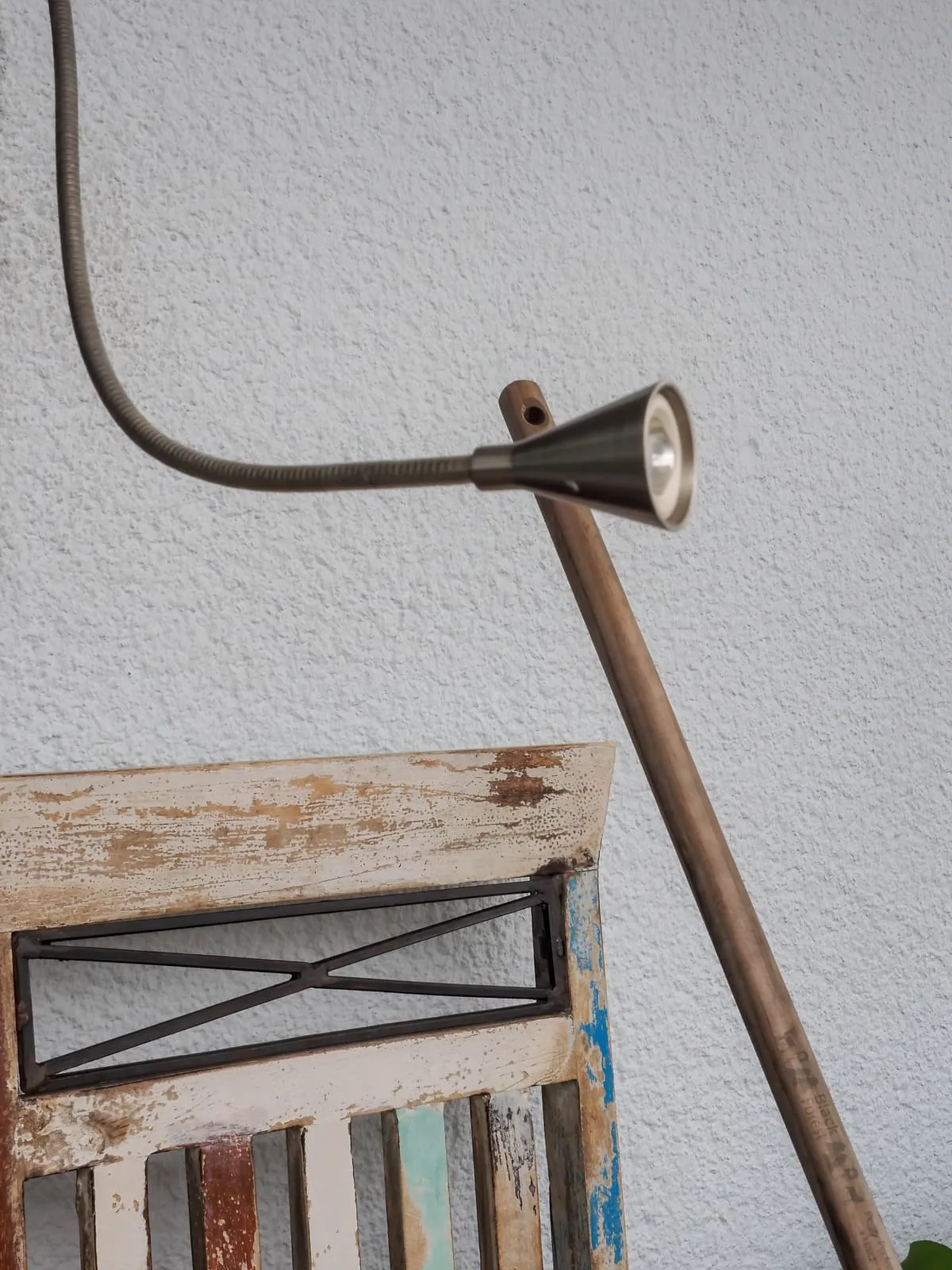 Bent spotlight on a rod over a weathered wooden chair, 2020