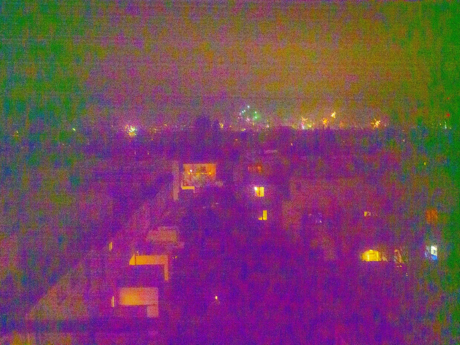 Colour noise over rooftops with a few lit windows at night, 2025