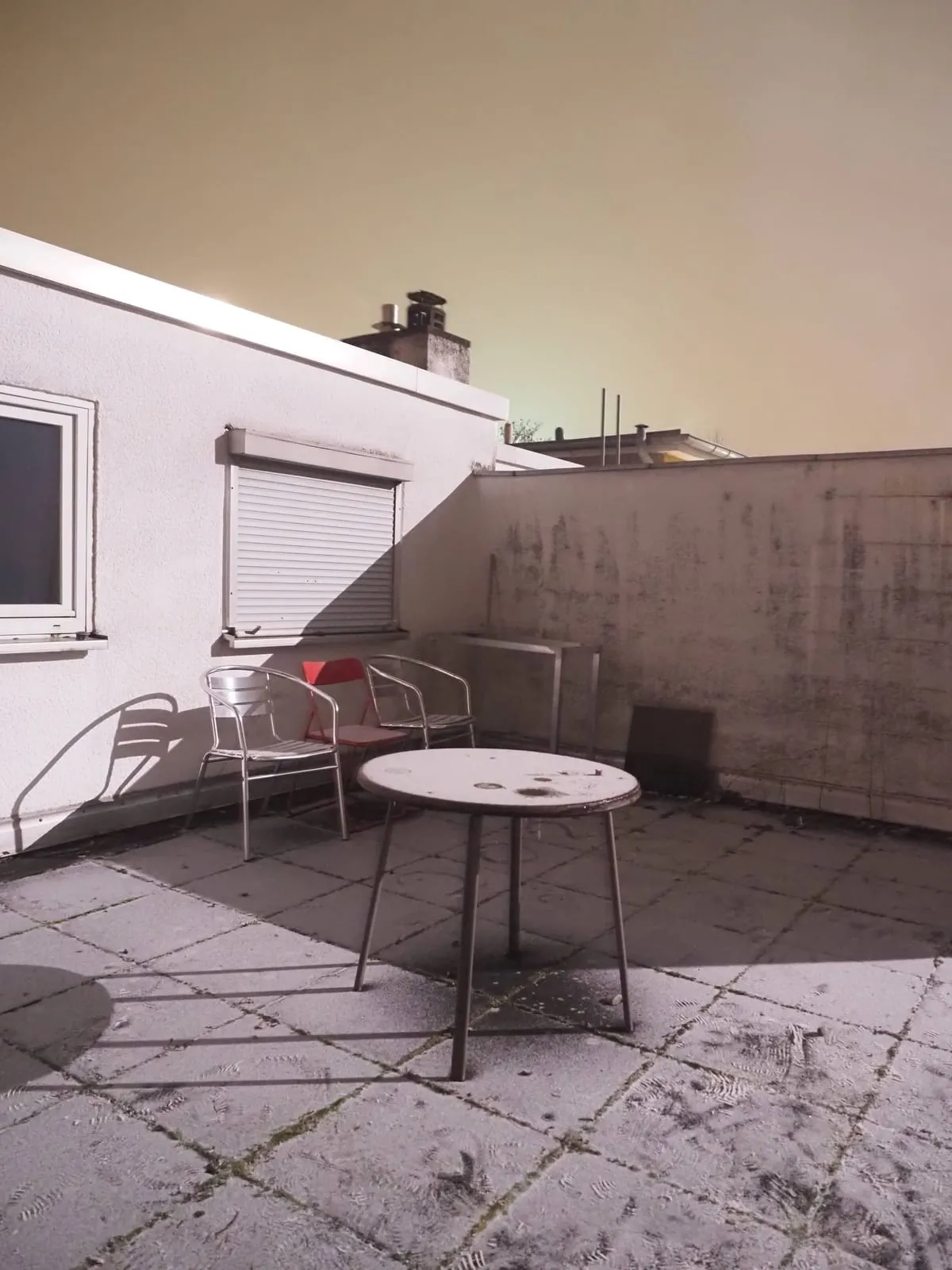 Roof terrace with a table and chairs under a pale night sky, 2025