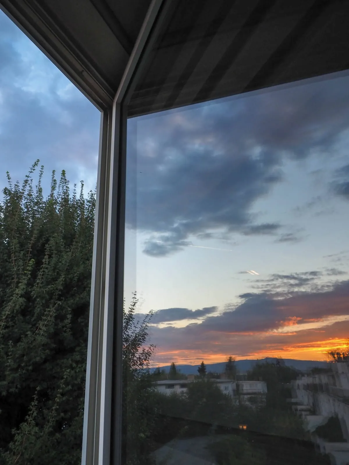 Sunset clouds seen through the corner of a glass shelter, 2020