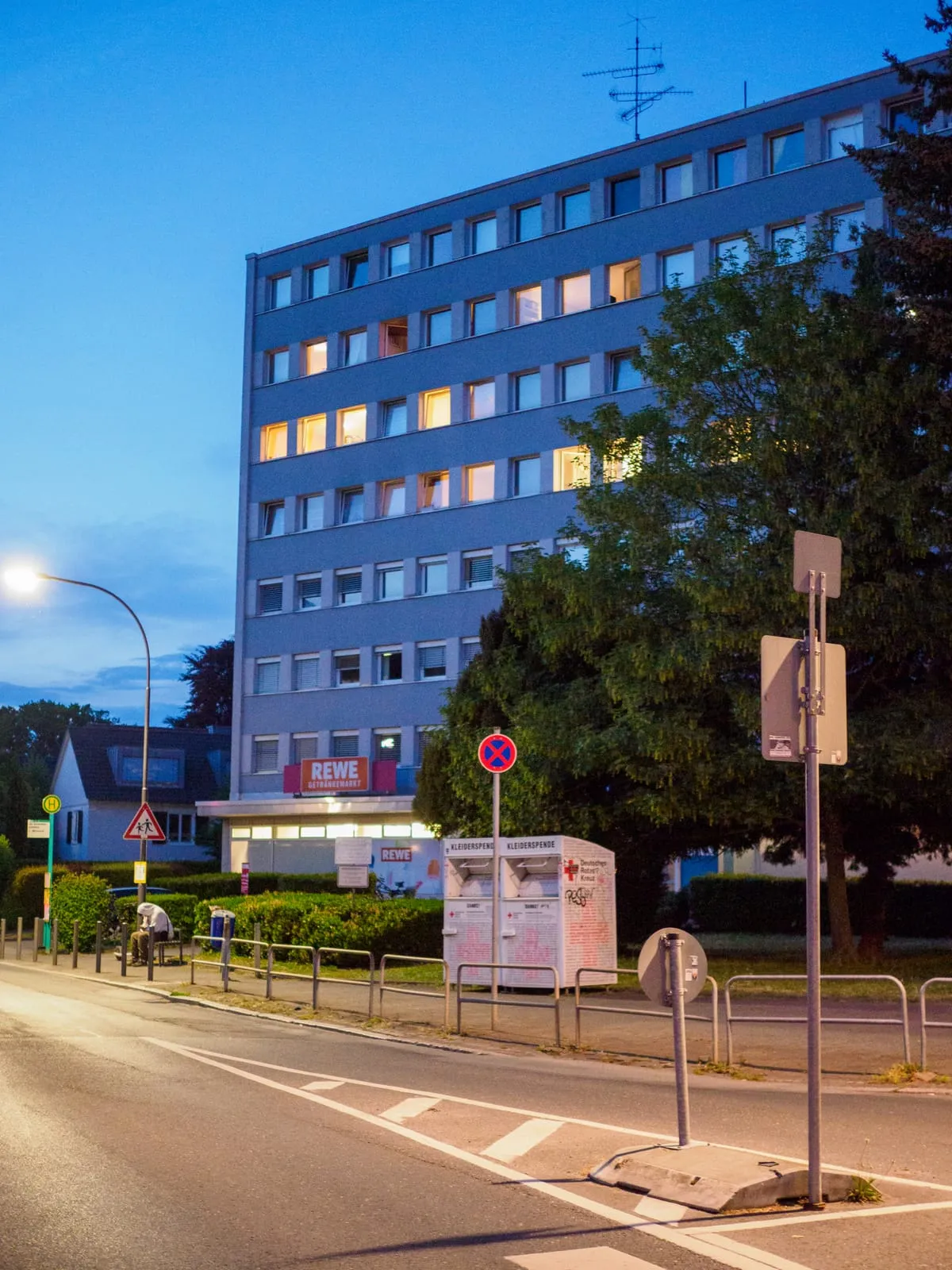 Blue office block at dusk with a few lit windows, 2026