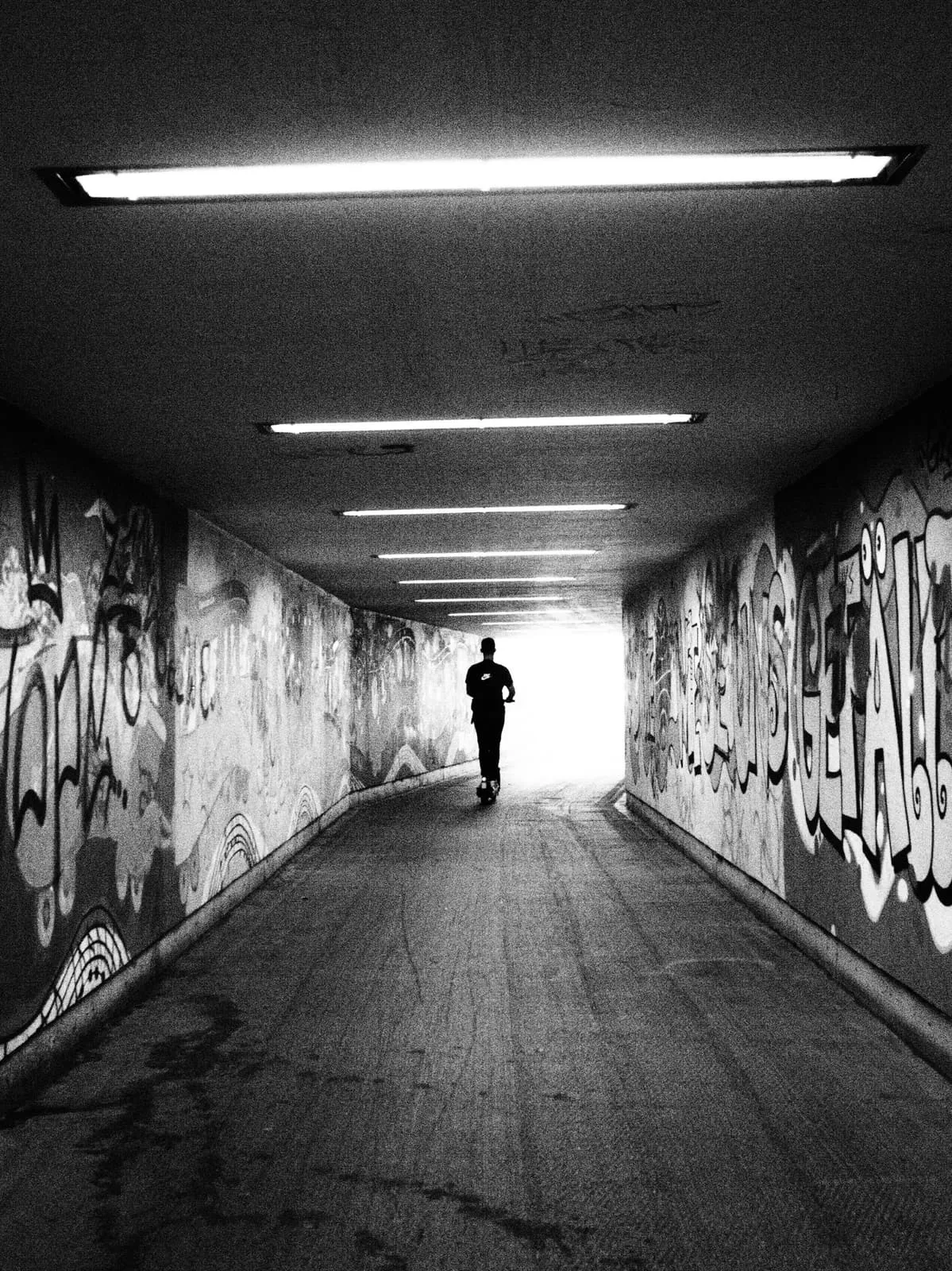 Black and white silhouette at the end of a graffiti tunnel, 2021