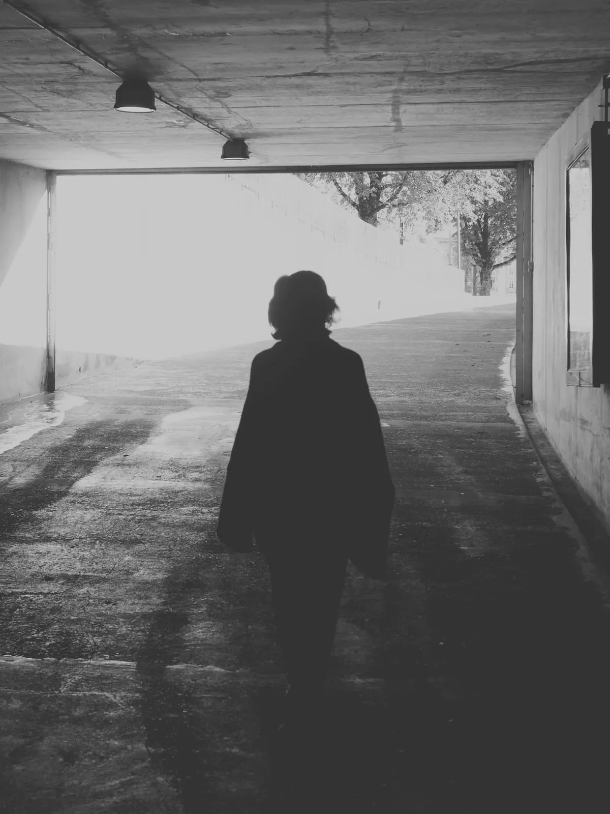 Black and white silhouette walking out of a foggy underpass, 2025