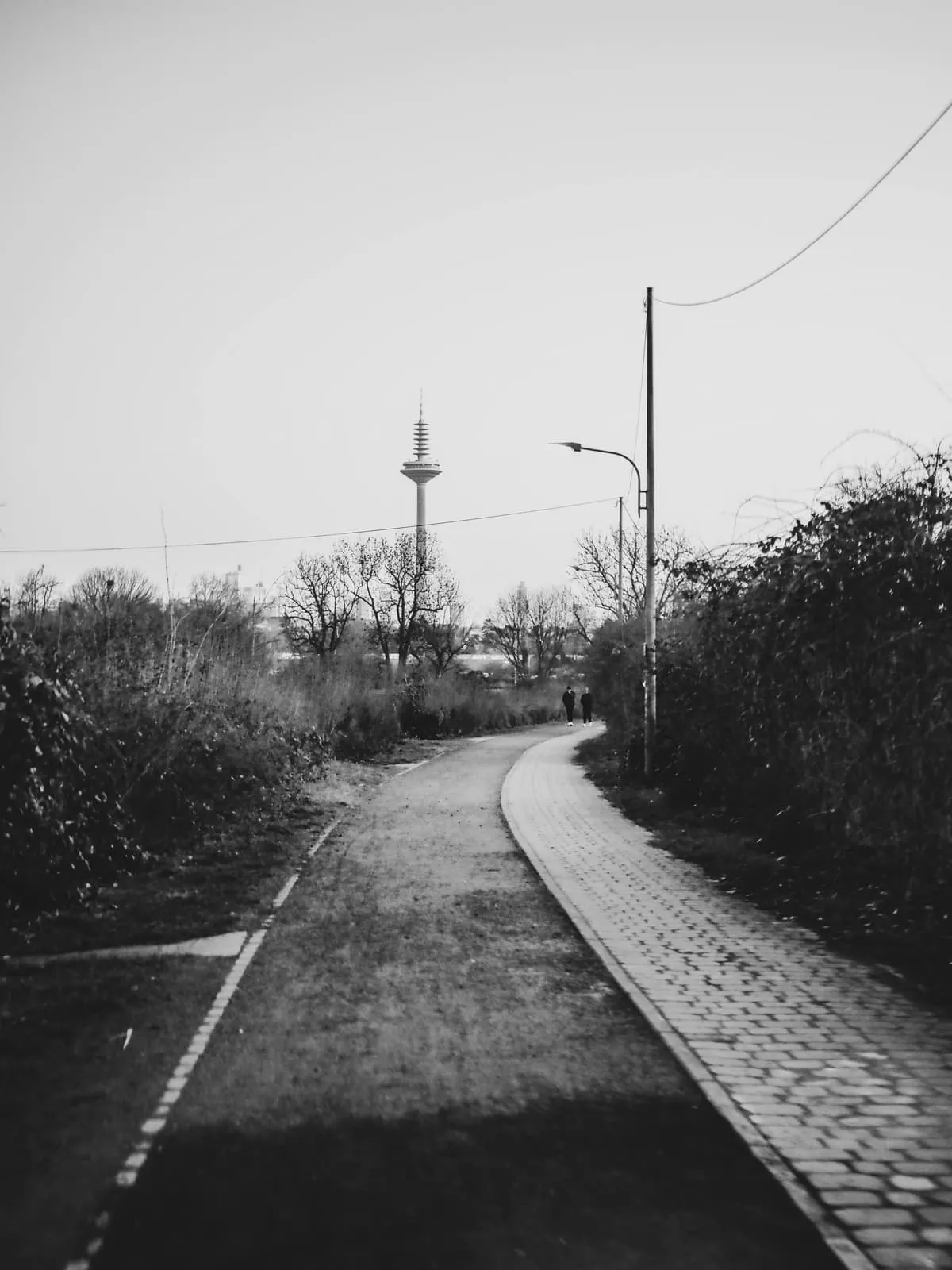 Black and white path curving toward a distant thin tower, 2025, Frankfurt am Main