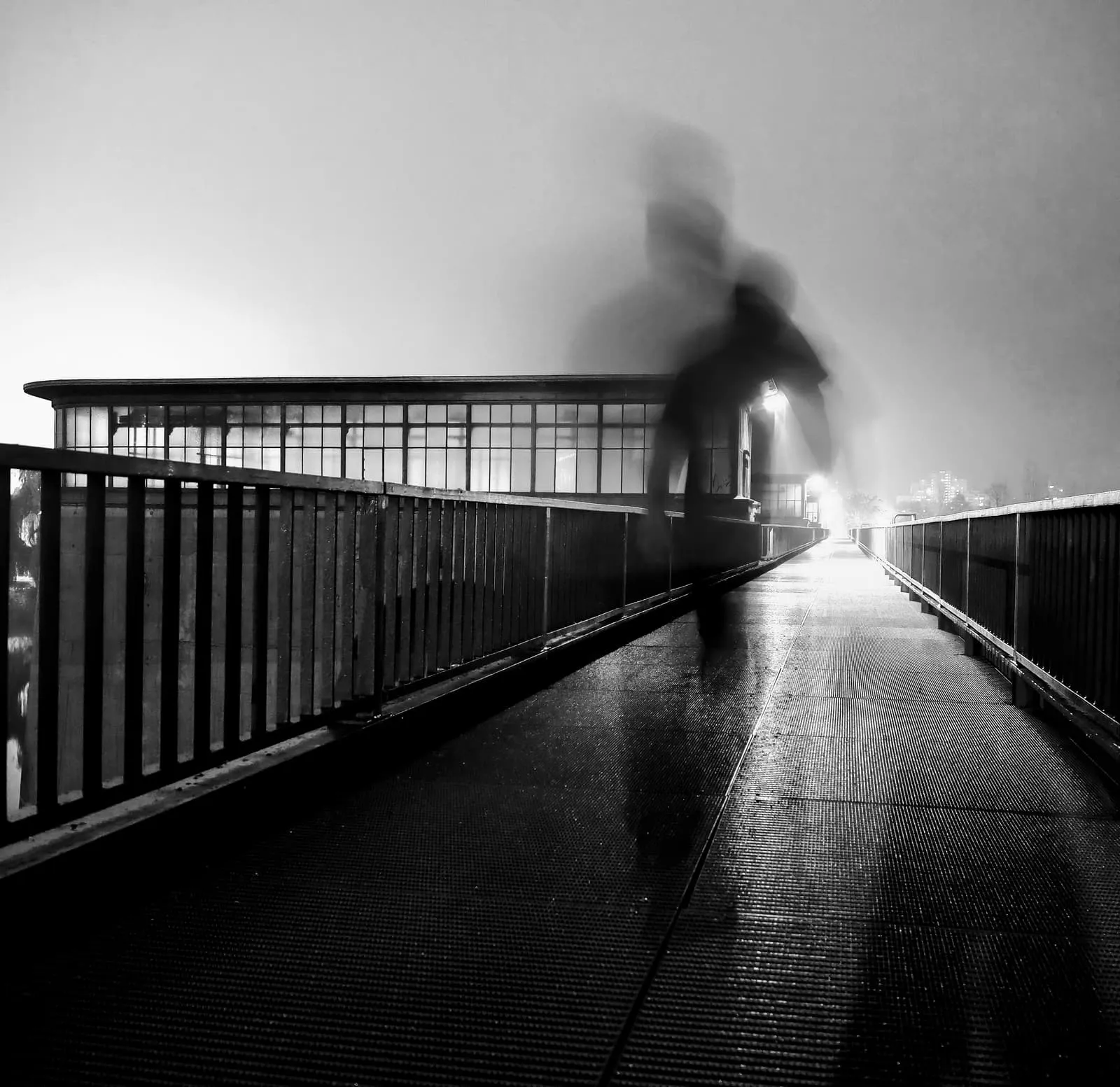 Black and white blurred figure on a footbridge in fog, 2019