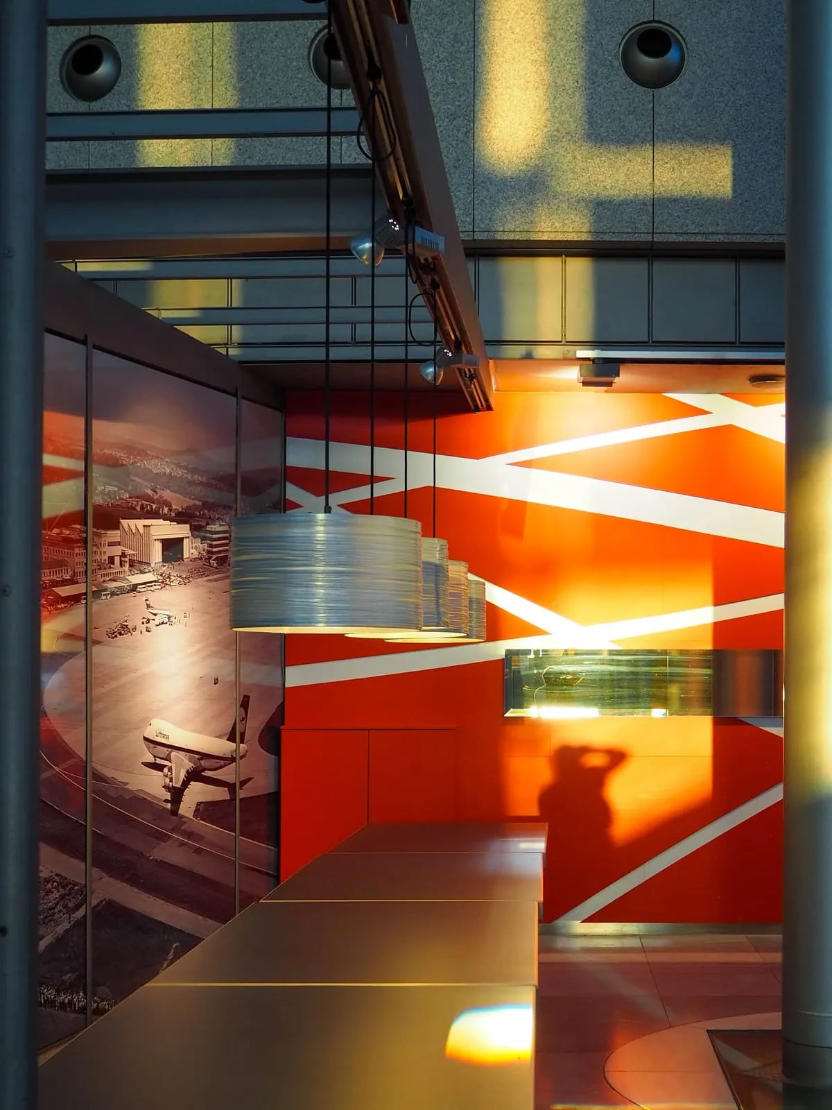 Orange lit interior behind glass, a photographer's shadow on the floor, 2019