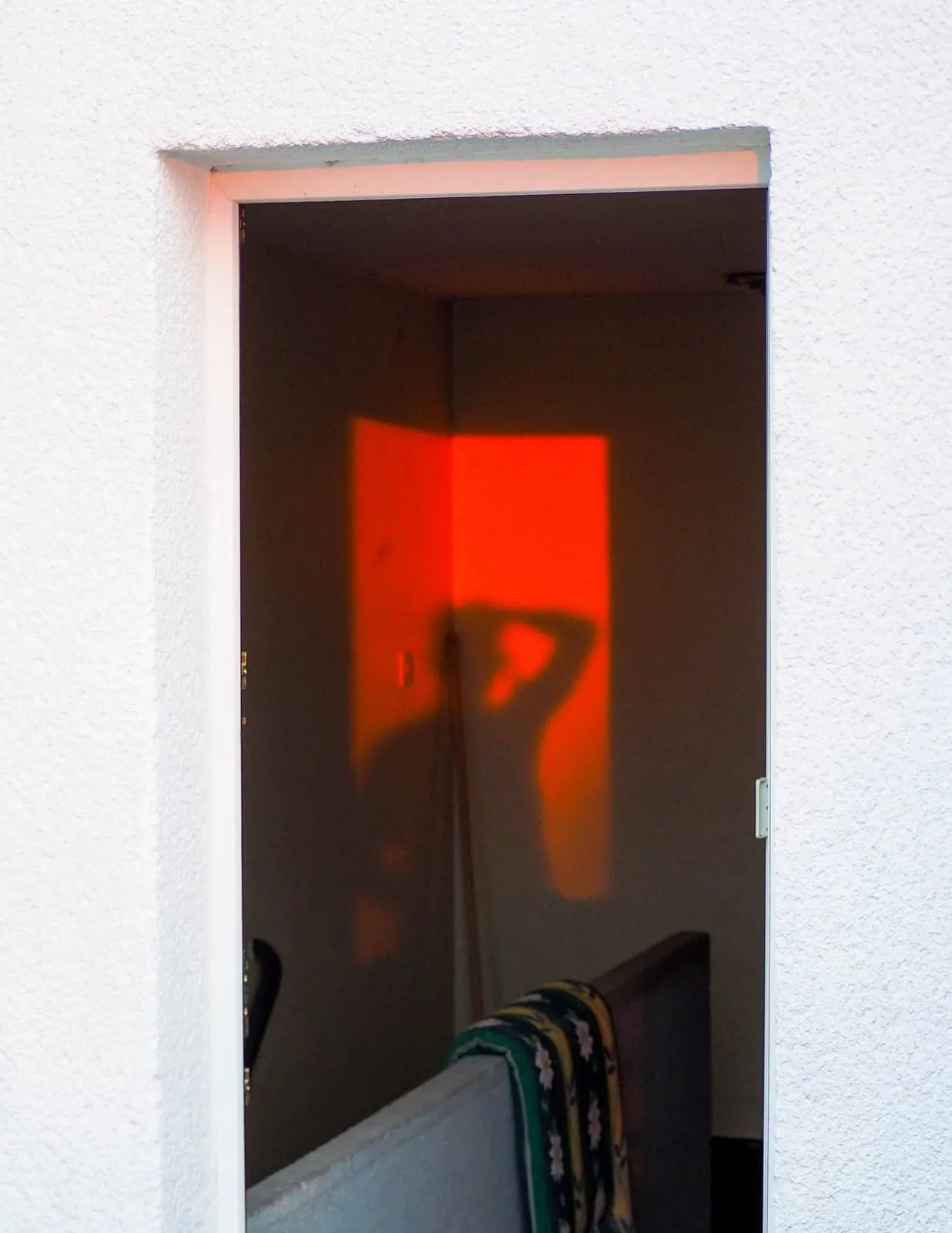 Doorway with orange light and the shadow of a raised arm, 2019