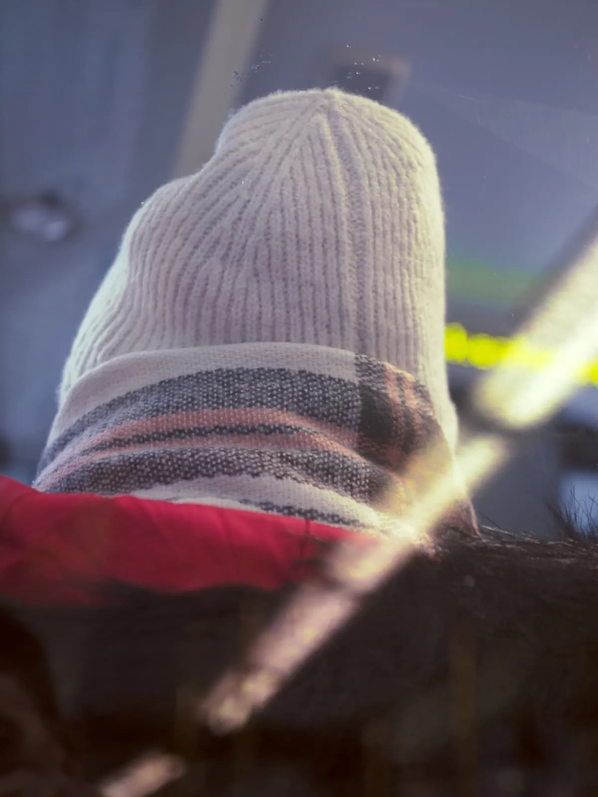 Back of a knitted hat against a tram window, 2026