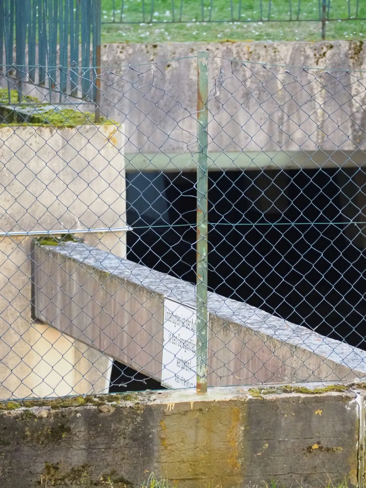 Concrete ramp and walls behind a chain link fence, 2025