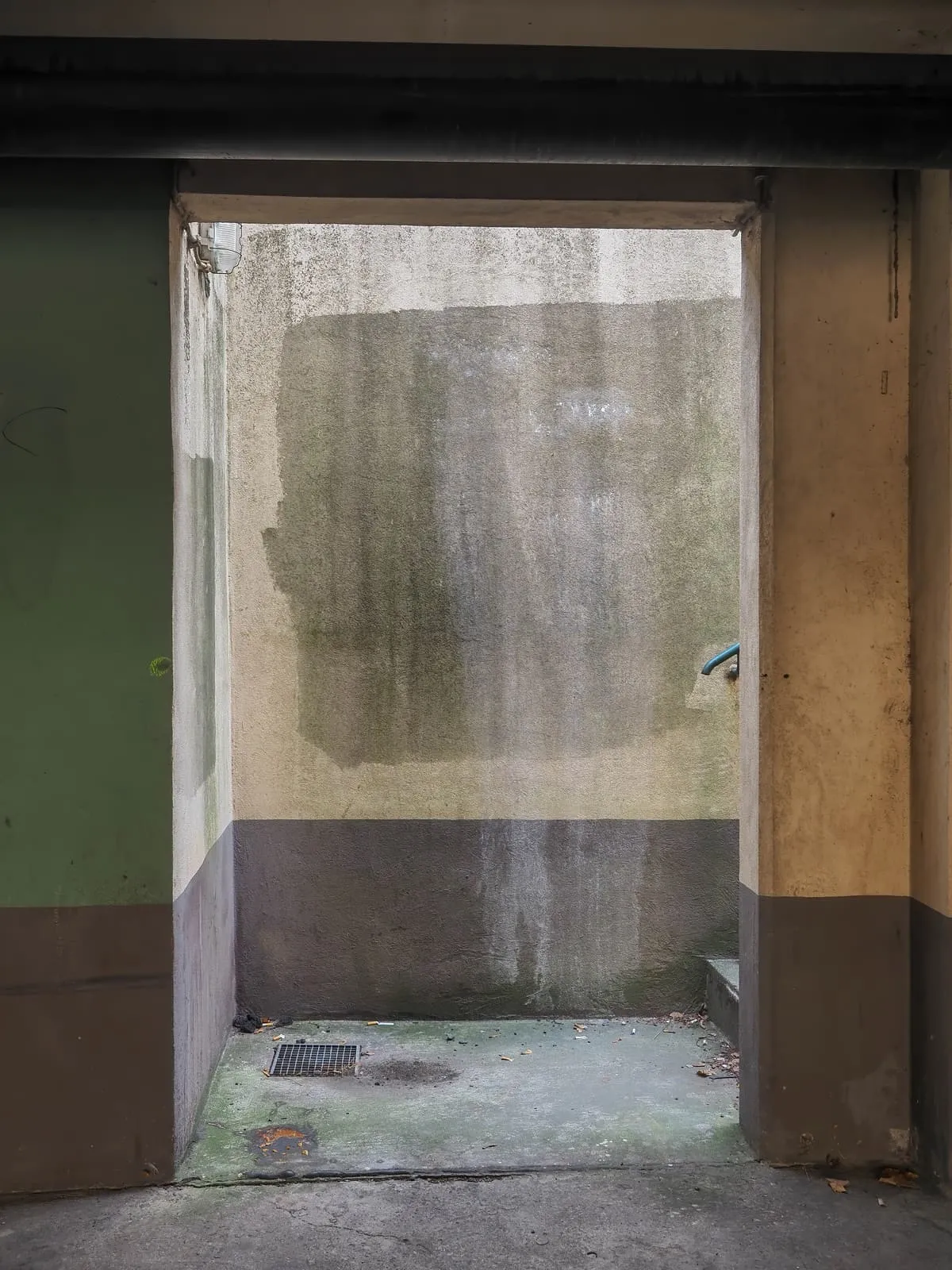 Doorway onto a small concrete yard with a dark stained wall, 2020