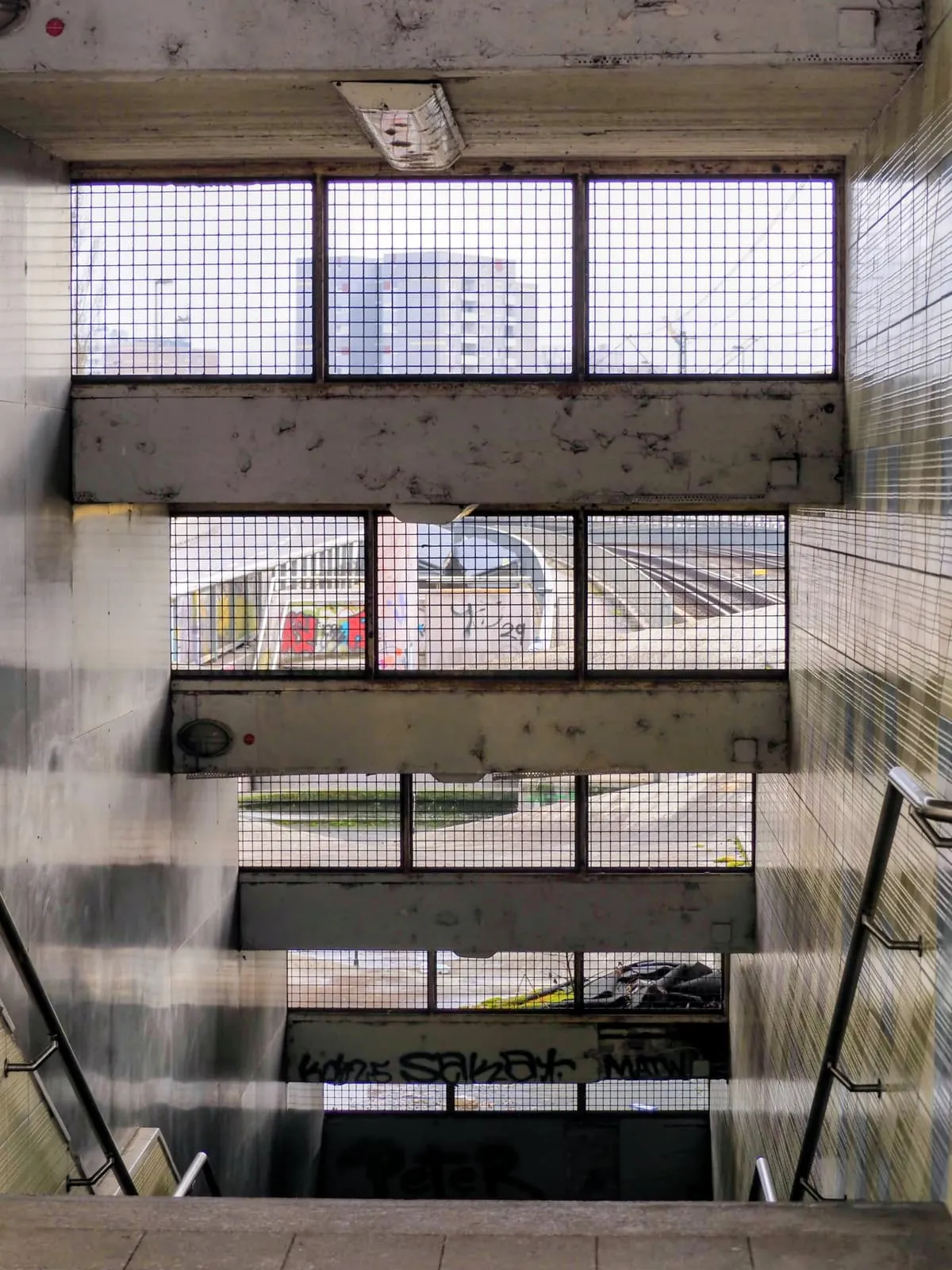 Stairwell with wire glass windows going down over rail tracks, 2025