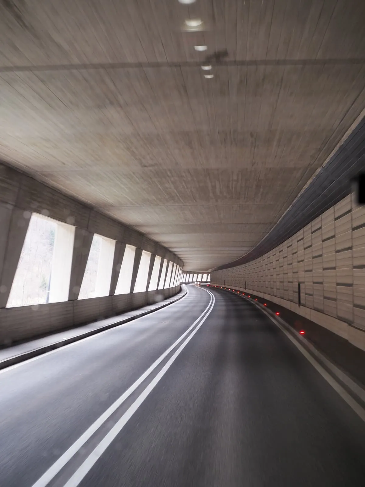 Empty road curving through a concrete gallery tunnel, 2026