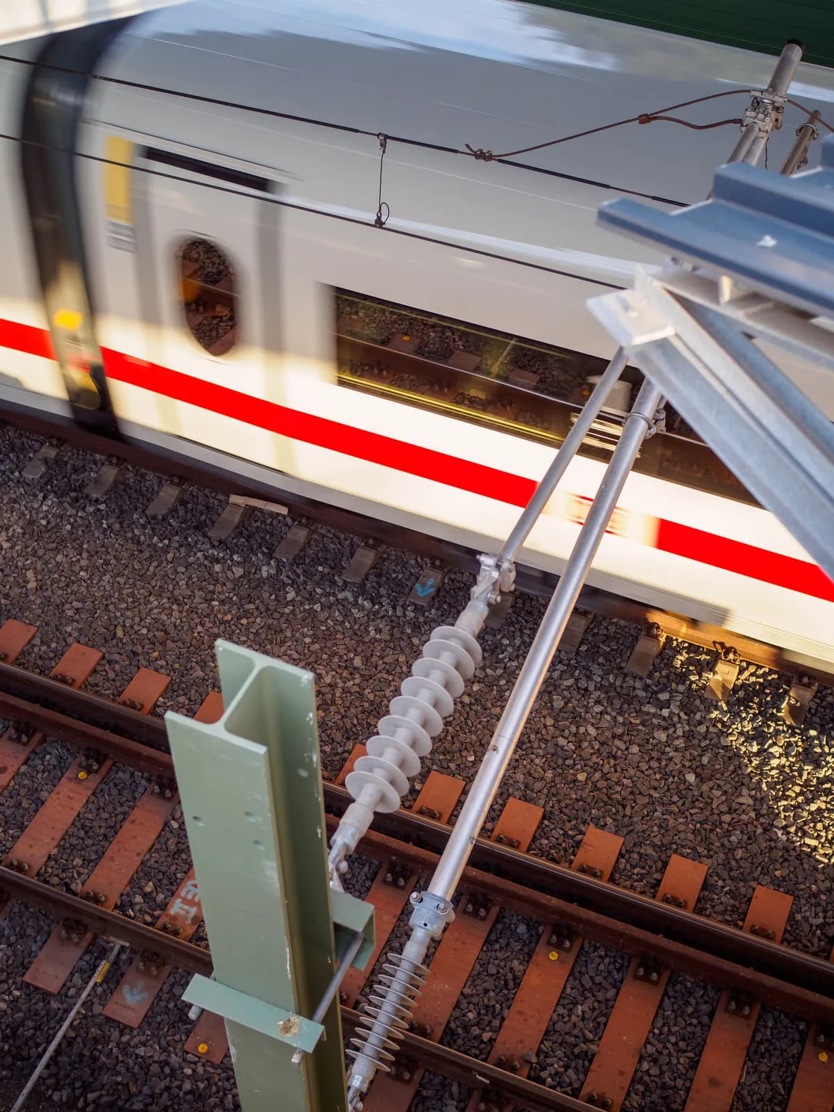 White train passing under a platform roof, from above, 2025