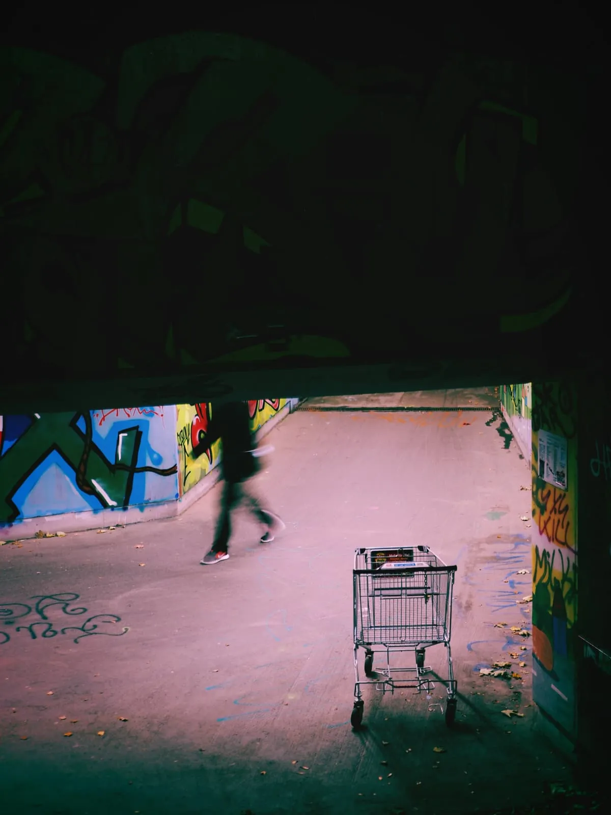 Legs walking past a shopping trolley in a pink underpass, 2021