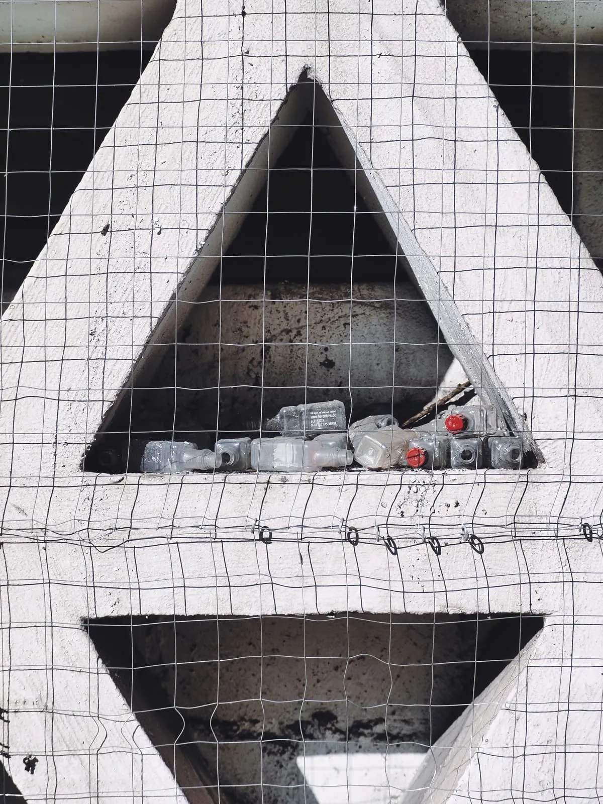 White concrete letter A behind wire mesh, bottles inside