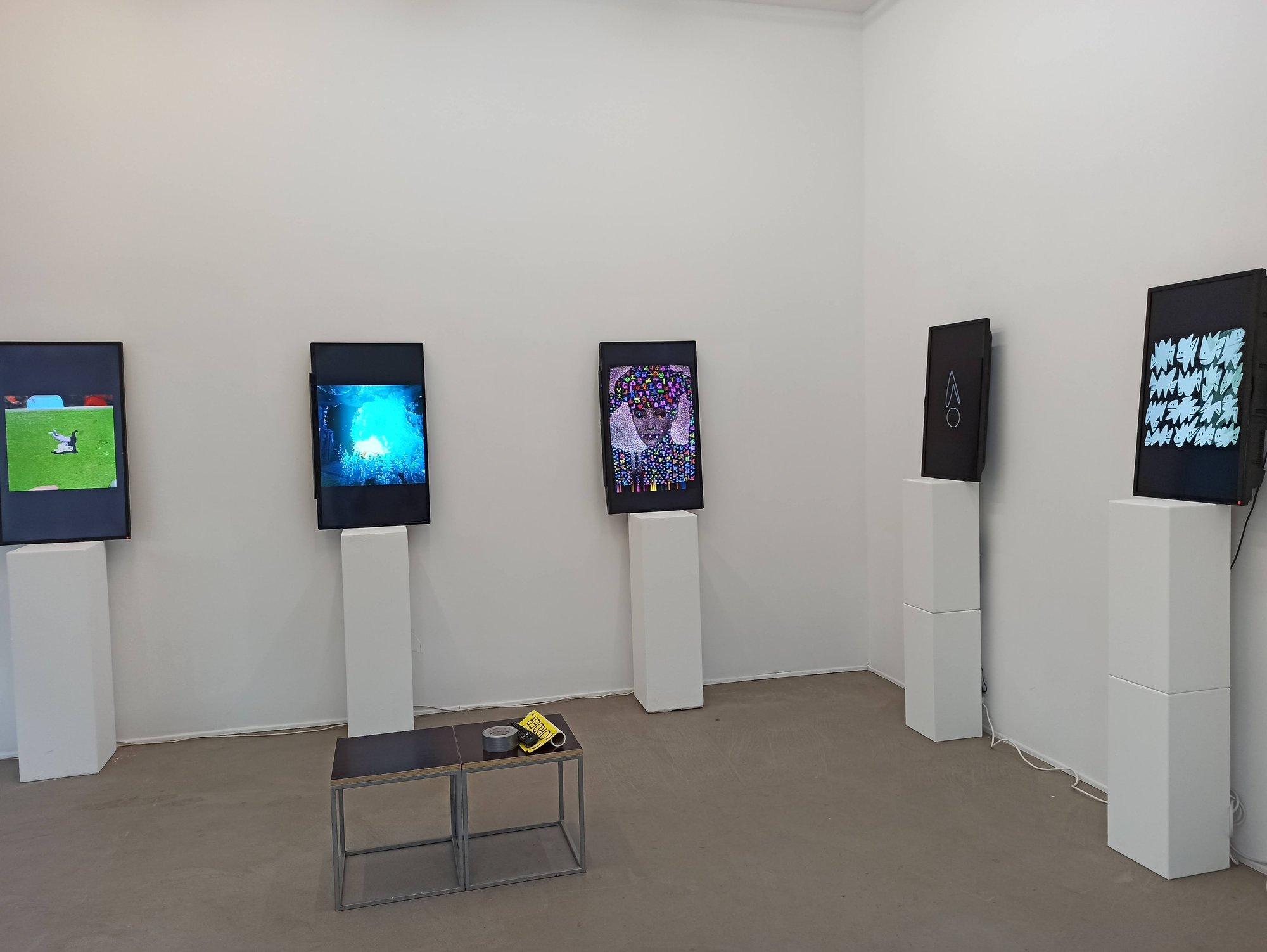 Fünf hochformatige Displays mit digitaler Kunst auf weißen Sockeln im Galerieraum